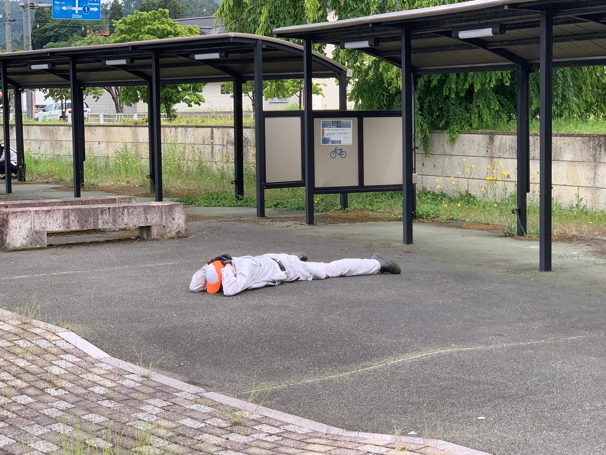 地面に伏せて頭部を守っている様子